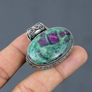 May include: A silver pendant featuring an oval green and pink gemstone set in a silver filigree frame.