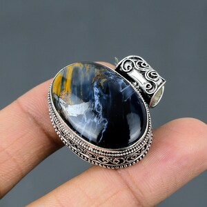 May include: A silver pendant with an oval blue and gold tiger's eye gemstone set in a silver ornate frame.
