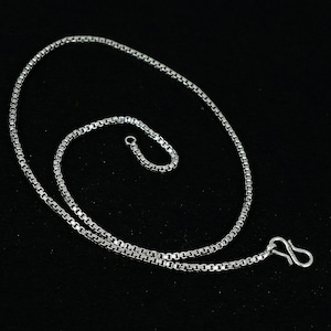 May include: A silver chain necklace with a box clasp and a lobster claw clasp. The chain is made of small, square links.