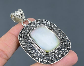 May include: A silver pendant with a white mother of pearl inlay. The pendant has a square shape with a decorative border.