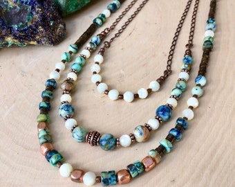 May include: Layered necklace featuring blue and green gemstone beads, copper beads, and white shell beads.