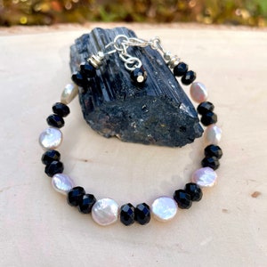 Peut inclure: Un bracelet noir et blanc avec des perles facett&eacute;es noires et des perles blanches nacr&eacute;es. Le bracelet est r&eacute;alis&eacute; avec un fermoir et une cha&icirc;ne en argent.