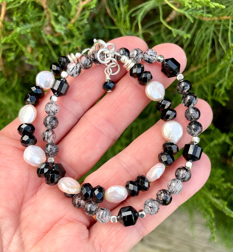 Peut inclure: Un bracelet compos&eacute; de perles d'onyx noir, de perles blanches et de quartz clair. Le bracelet est fait de m&eacute;tal argent&eacute;.