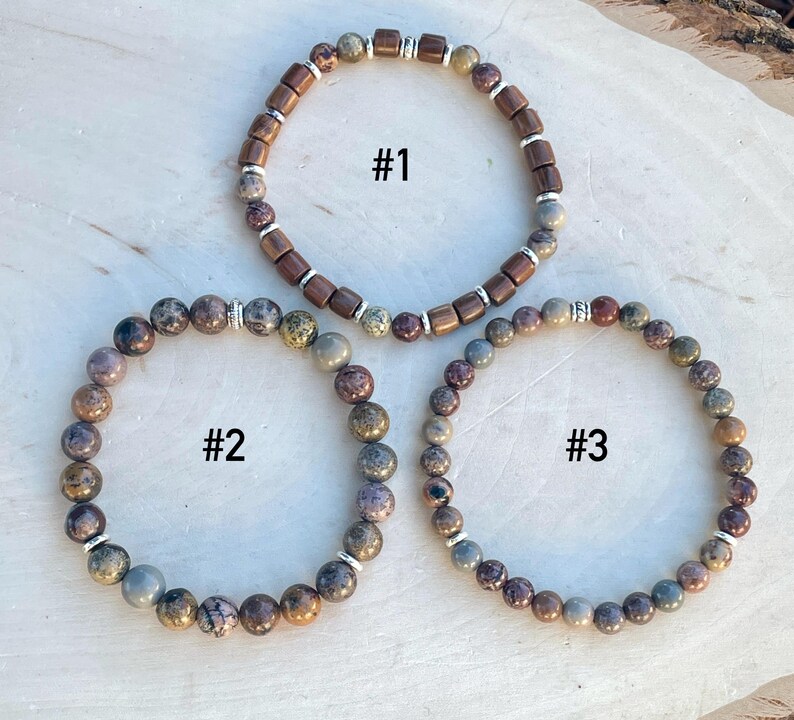 K&ouml;nnte beinhalten: Drei Armb&auml;nder mit braunen und grauen Perlen. Die Armb&auml;nder sind mit 1, 2 und 3 nummeriert.