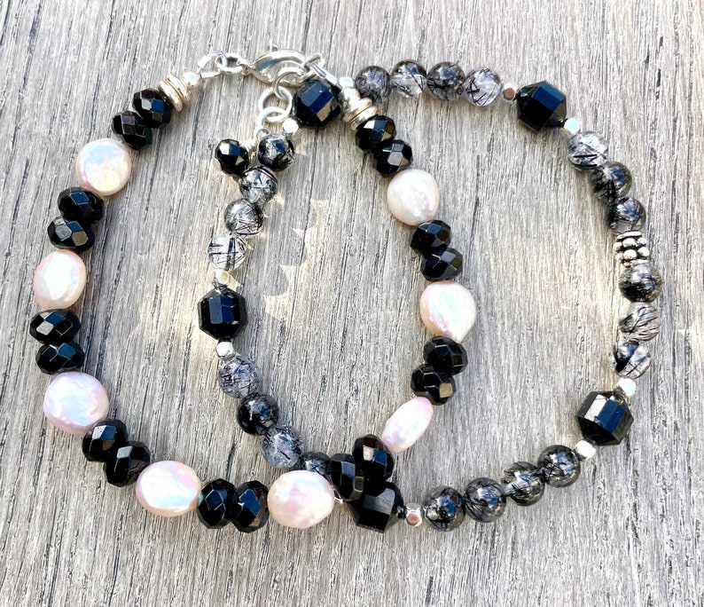 Peut inclure: Deux bracelets avec des perles noires, blanches et grises. Un bracelet a des perles noires et blanches, tandis que l'autre a des perles noires et grises.