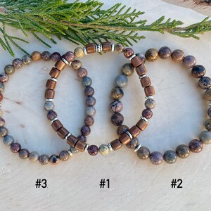 K&ouml;nnte beinhalten: Drei Armb&auml;nder aus braunen und grauen Steinen mit silbernen Akzenten. Die Armb&auml;nder sind &uuml;bereinander gestapelt und mit #1, #2 und #3 beschriftet.