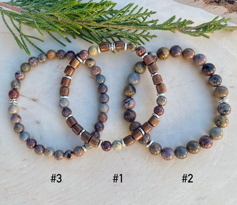 K&ouml;nnte beinhalten: Drei Armb&auml;nder aus braunen und grauen Steinen mit silbernen Akzenten. Die Armb&auml;nder sind &uuml;bereinander gestapelt und mit #1, #2 und #3 beschriftet.