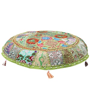 Puede incluir: Cojín redondo para el suelo con un diseño de patchwork en tonos verdes, rojos, azules y dorados. El cojín tiene un borde verde y borlas decorativas. El diámetro es de unos 61 cm.