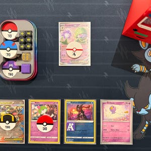 Pode incluir: Uma cole&ccedil;&atilde;o de cartas colecion&aacute;veis Pok&eacute;mon incluindo Gardevoir ex, Rayquaza ex, Ralts, Radiant Greninja e Drifloon, junto com uma lata de metal contendo dados de dano, um marcador de energia de fogo e uma caixa de baralho vermelha num tapete.