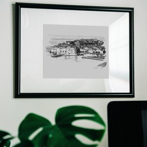 Puede incluir: Un dibujo en blanco y negro de una ciudad, enmarcado en un marco negro. El dibujo est&aacute; sobre un fondo gris claro.
