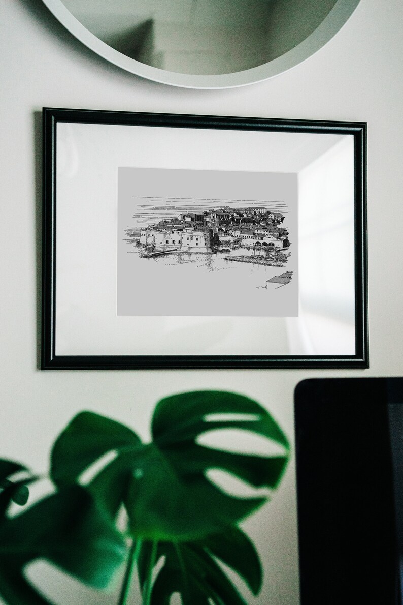Puede incluir: Un dibujo en blanco y negro de una ciudad, enmarcado en un marco negro. El dibujo est&aacute; sobre un fondo gris claro.