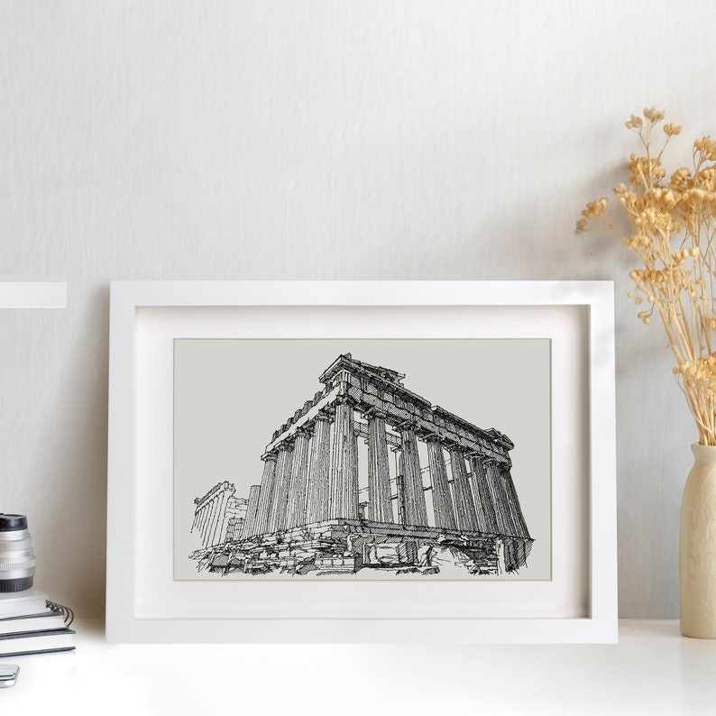 May include: A framed black and white architectural print of the Parthenon. The artwork is displayed in a white frame and set against a light gray background. The print is a detailed line drawing of the ancient Greek temple.