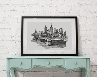 Könnte beinhalten: Schwarz-weiß-Zeichnung einer Skyline mit einer Brücke im Vordergrund. Die Zeichnung ist in einem schwarzen Rahmen gerahmt und hängt an einer weißen Backsteinwand über einer hellblauen Kommode.