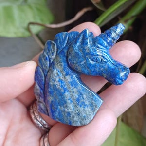 Peut inclure: Une sculpture de tête de licorne en lapis-lazuli bleu. La sculpture est détaillée et présente un marbrage blanc et or.