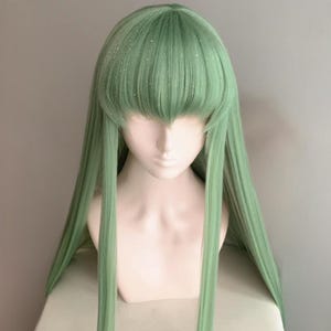 Peut inclure: Une perruque longue, droite et verte avec une frange. La perruque a une légère brillance sur toute sa surface.