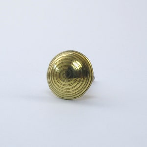 May include: A gold-toned metal knob with a spiral design.