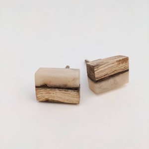 May include: Two wooden cabinet knobs with a light brown wood base and a white resin top. The resin has a natural, cloudy appearance.