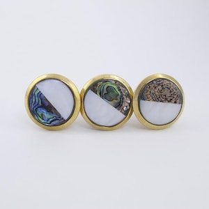 May include: Three round brass cabinet knobs with a white half-circle and a half-circle of iridescent abalone shell.