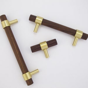 May include: Three cabinet knobs with a dark wood finish and gold metal accents. The knobs are in different sizes and shapes.