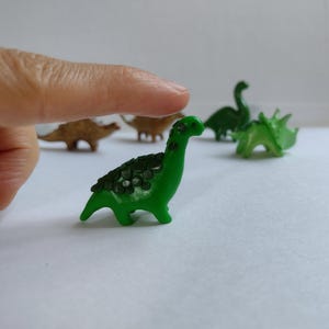 Tiny dinosaur figurine in green. Diplodocus dinosaur figurine. Small sculpture of dinosaur.