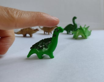 Tiny dinosaur figurine in green. Diplodocus dinosaur figurine. Small sculpture of dinosaur.
