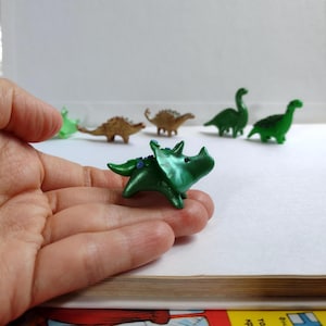 Winziger Dinosaurier in grün. Triceratops Dinosaurier Figur. Kleine Skulptur von einem Dinosaurier. Spielzeugbegleiter im Taschenformat.