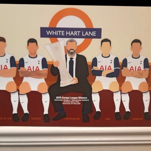 Può includere: Illustrazione di una squadra di calcio con un allenatore che tiene un trofeo. I giocatori indossano uniformi bianche e blu navy con il logo AIA. Il testo "WHITE HART LANE" è in alto, con i nomi dei giocatori in basso.