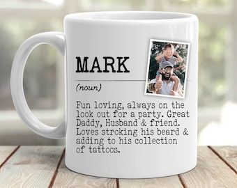 May include: White ceramic mug with the name "MARK" in bold black letters. The mug includes a definition and a small photo. The definition describes the person as fun-loving, a great dad, husband, and friend.