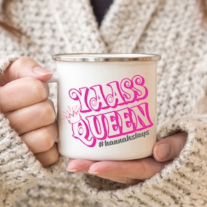 Op de afbeelding: Witte emaille mok met een roze ontwerp met de tekst "Y'all Queen" met een kroon boven het woord "Queen" en de tekst "#hannahslays" eronder.