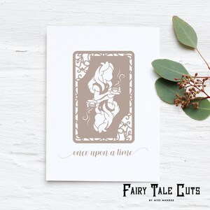 May include: A white card with a brown silhouette of Alice in Wonderland holding a teacup. The silhouette is surrounded by a decorative frame. The text "once upon a time" is written below the silhouette. The card has the text "Fairy Tale Cuts by Miss Mandee" at the bottom.