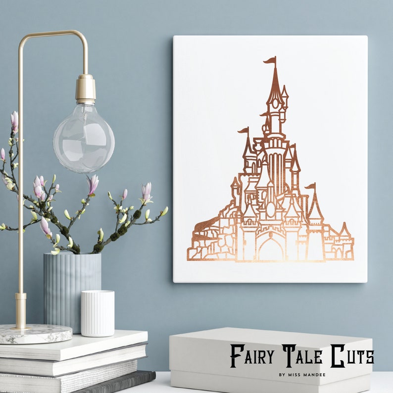 May include: A white canvas print with a copper-colored outline of a fairytale castle. The castle has multiple towers and a pointed roof. The text "Fairy Tale Cuts by Miss Mandee" is printed below the image.