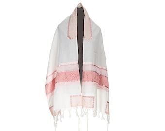 May include: White prayer shawl with pink accents. The shawl features pink ribbon stripes and decorative squares. The edges are finished with tassels. The shawl is draped over a dark form.