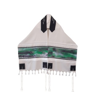 May include: White prayer shawl with black stripes and green watercolor design. The shawl has black panels with Hebrew text, and tassels along the bottom edge. A religious garment.