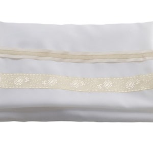 May include: A rectangular white fabric piece folded horizontally, featuring two horizontal decorative bands. The top band is a plain beige ribbon, while the bottom band is a wider beige ribbon adorned with a repeating white paisley pattern.