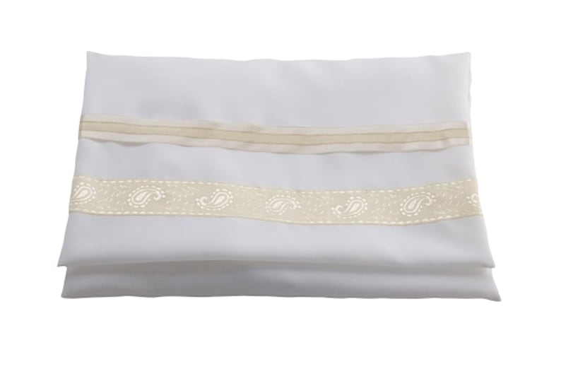 May include: A rectangular white fabric piece folded horizontally, featuring two horizontal decorative bands. The top band is a plain beige ribbon, while the bottom band is a wider beige ribbon adorned with a repeating white paisley pattern.
