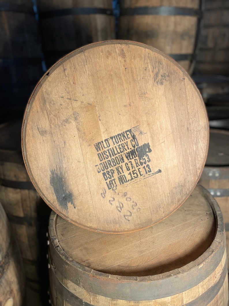 K&ouml;nnte beinhalten: Ein Holzfass mit dem Text "WILD TURKEY DISTILLERY CO. BOURBON WHISKY DSP KY 67-RC3 LOT NO.15E13" auf der Oberseite.