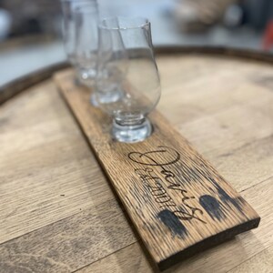 Może przedstawiać: Drewniana taca do degustacji whisky z trzema szklankami i napisem "Jack's Est. 2001".