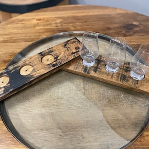 Może przedstawiać: Trzy przezroczyste szklanki do degustacji whisky stoją na drewnianej tacy z trzema wgłębieniami. Taca wykonana jest z odzyskanego drewna i ma ciemnobrązowe zabarwienie. Taca stoi na drewnianym stole.