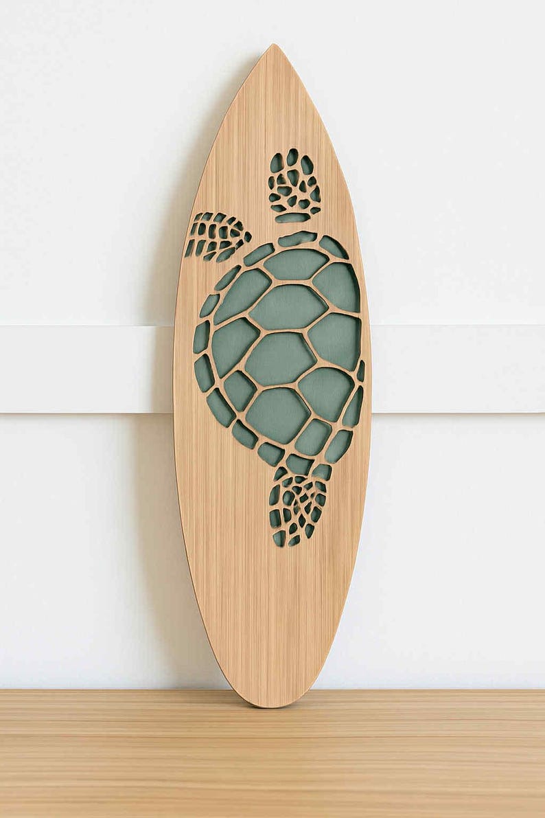 May include: Wooden surfboard-shaped wall art featuring a laser-cut sea turtle design. The turtle's shell is filled with a teal-colored background. The surfboard is made of light-colored wood and is mounted on a white wall.
