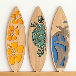 May include: Three wooden surfboards with decorative cutouts. One features orange hibiscus flowers, another a teal turtle, and the last a palm tree with blue accents. The surfboards are displayed on a wooden shelf.