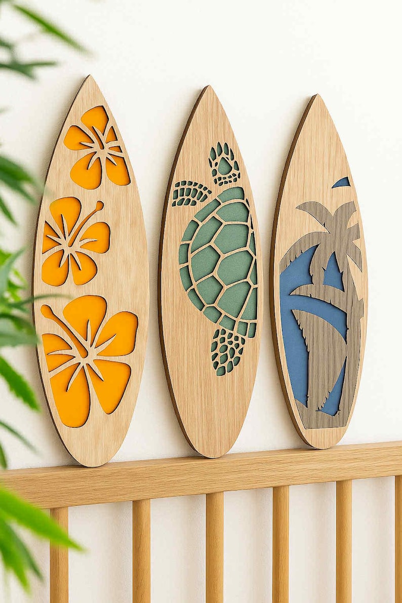 May include: Three wooden surfboard-shaped wall decorations. One features orange hibiscus flowers, another a green turtle, and the last a blue and gray palm tree. The surfboards are mounted on a light-colored wooden rail.