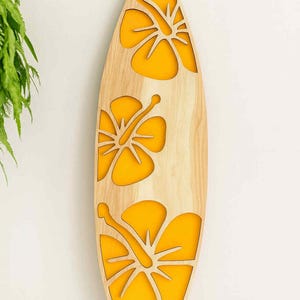May include: Wooden surfboard-shaped wall art with three yellow hibiscus flower cutouts. The surfboard is made of light-colored wood and is mounted on a white wall. The yellow flowers add a pop of color.