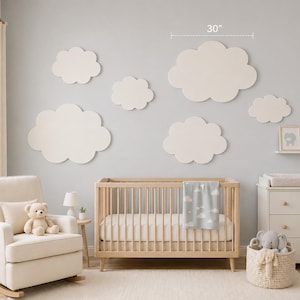Könnte beinhalten: Ein Kinderzimmer mit hellblauer Wand, verziert mit weißen wolkenförmigen Wanddekorationen. Ein Holzbettchen, ein Schaukelstuhl und eine Kommode vervollständigen den Raum. Die größte Wolke misst 76 cm.