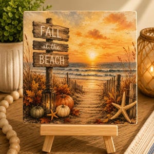 May include: A square decorative sign featuring a sunset beach scene with a wooden signpost that reads FALL at the BEACH. The image includes pumpkins, a lantern, autumn leaves, and a starfish along a sandy path leading to the ocean waves.