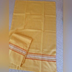 May include: A yellow gingham patterned kitchen towel and matching folded hand towel. The towels have a decorative border with white, orange, and yellow stitching. The towels are made of a soft fabric.