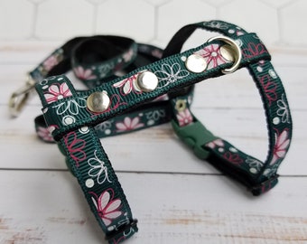 Puede incluir: Un arnés para perro floral verde y rosa con detalles metálicos plateados y una correa a juego.