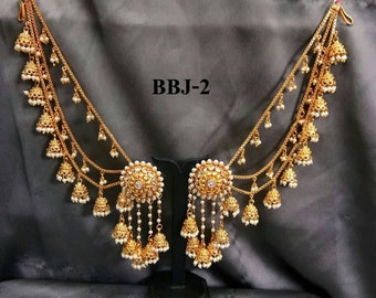 May include: A pair of gold-tone earrings with a dangling chain and multiple small bells. The earrings feature a large, round, white stone in the center. The earrings are labeled "BBJ-2".