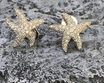 May include: A pair of silver starfish earrings with a sparkling diamond-like finish.