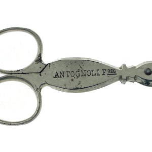 Puede incluir: Cortapuros de metal plateado con un diseño de tijeras de doble extremo. El cortapuros tiene un mango curvo con la inscripción "ANTOGNOLI F.REG."