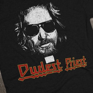 May include: Black t-shirt with a white image of a man wearing sunglasses and a clerical collar. The text "Dudest Priest" is printed in red and yellow below the image.